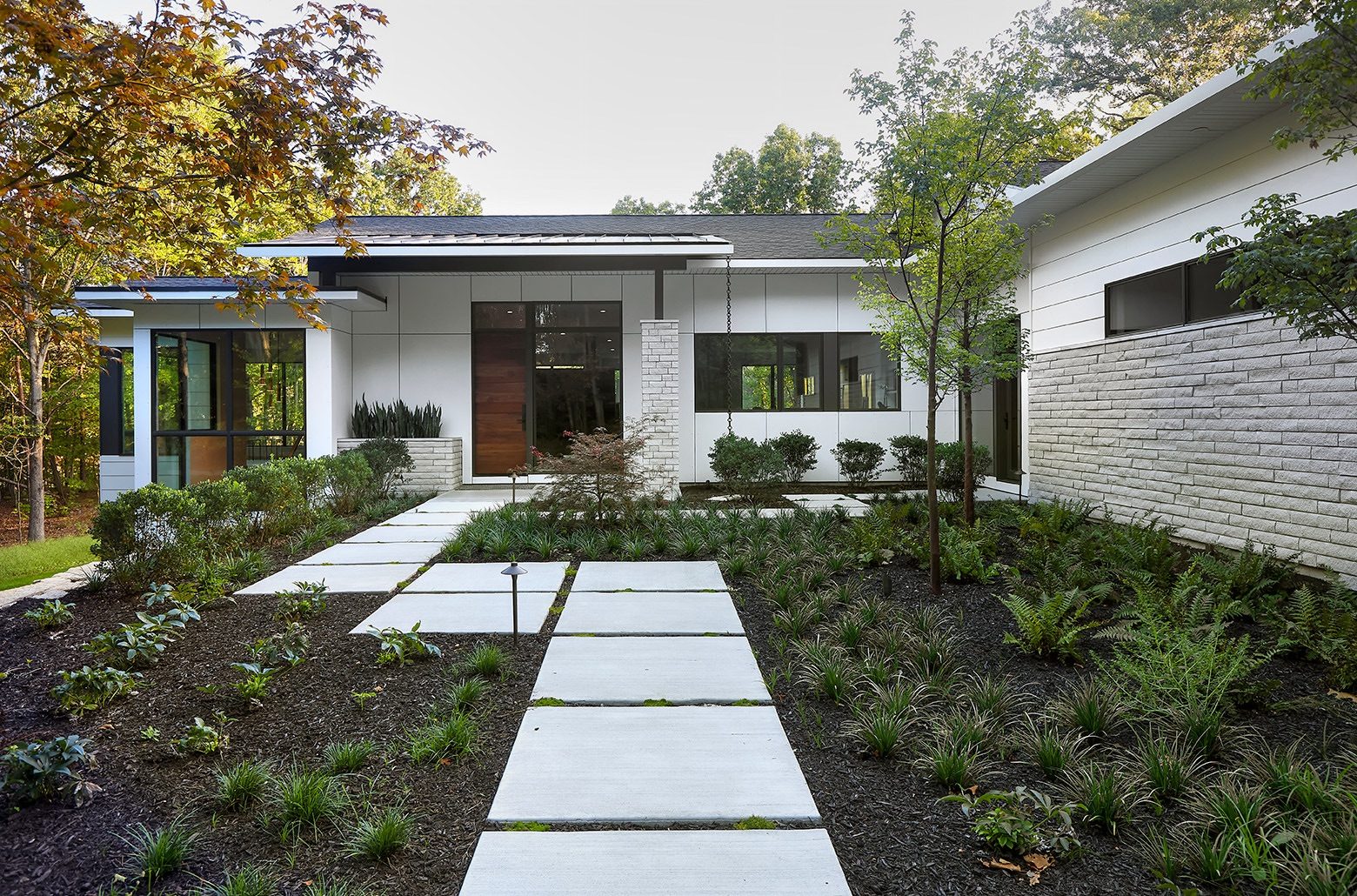 White modern home with a sidewalk set into landscaping