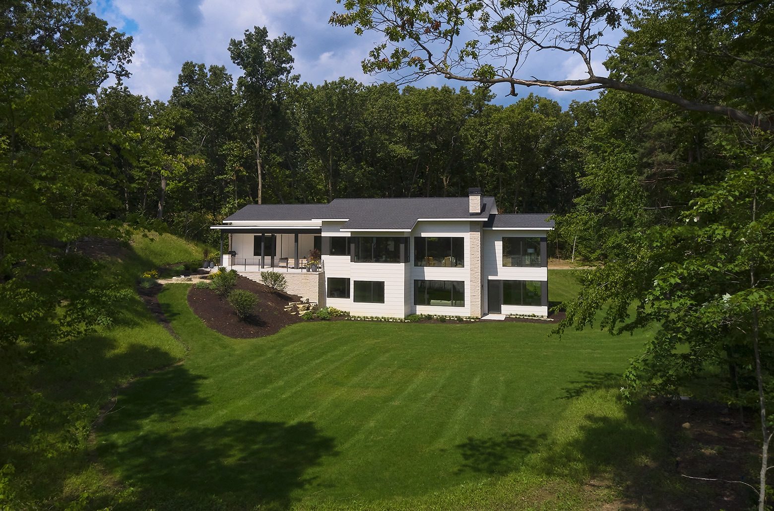 Distant rear view of a white contemporary home set into a hill