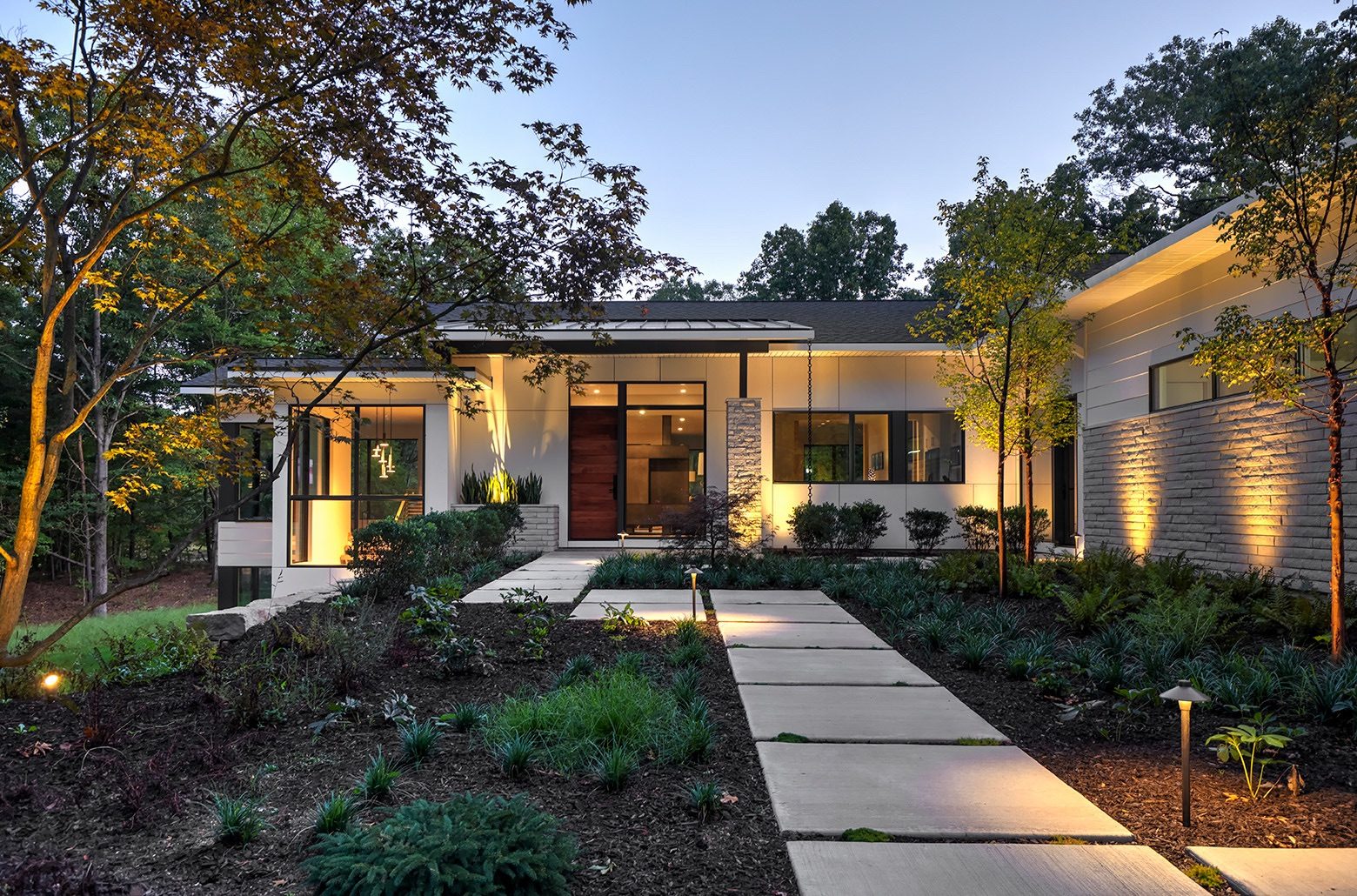 Modern home with a landscaped sidewalk lit up at night